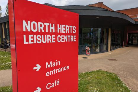 Red sign for North Herts Leisure Centre, outside the main entrance.