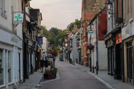 Royston town centre, looking up a high street with shops on either side of a narrow road.