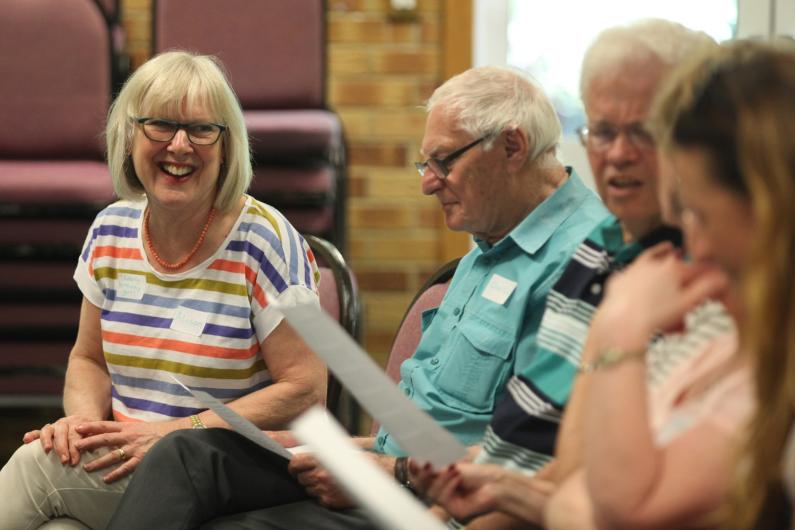 Older people sitting with song sheets