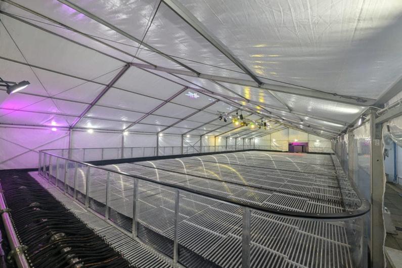 The Ice Rink in the process of being built, in large white marquee, with metal foundation but no ice on top yet. 