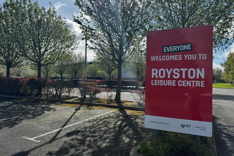 Large red sign in a car park in front of some trees stating: Everyone welcomes you to Royston Leisure Centre