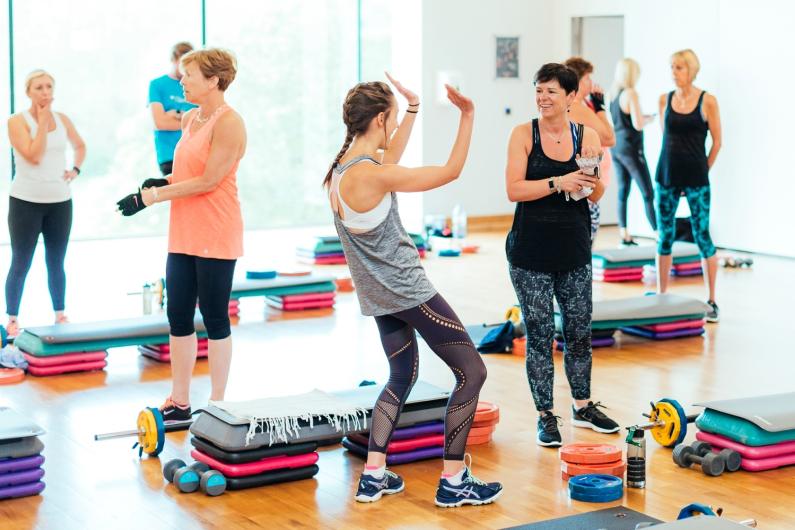 Women at a group exercise class with steps & weights