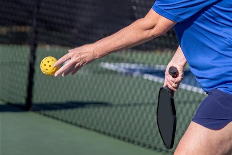 Close up of someone serving a pickleball